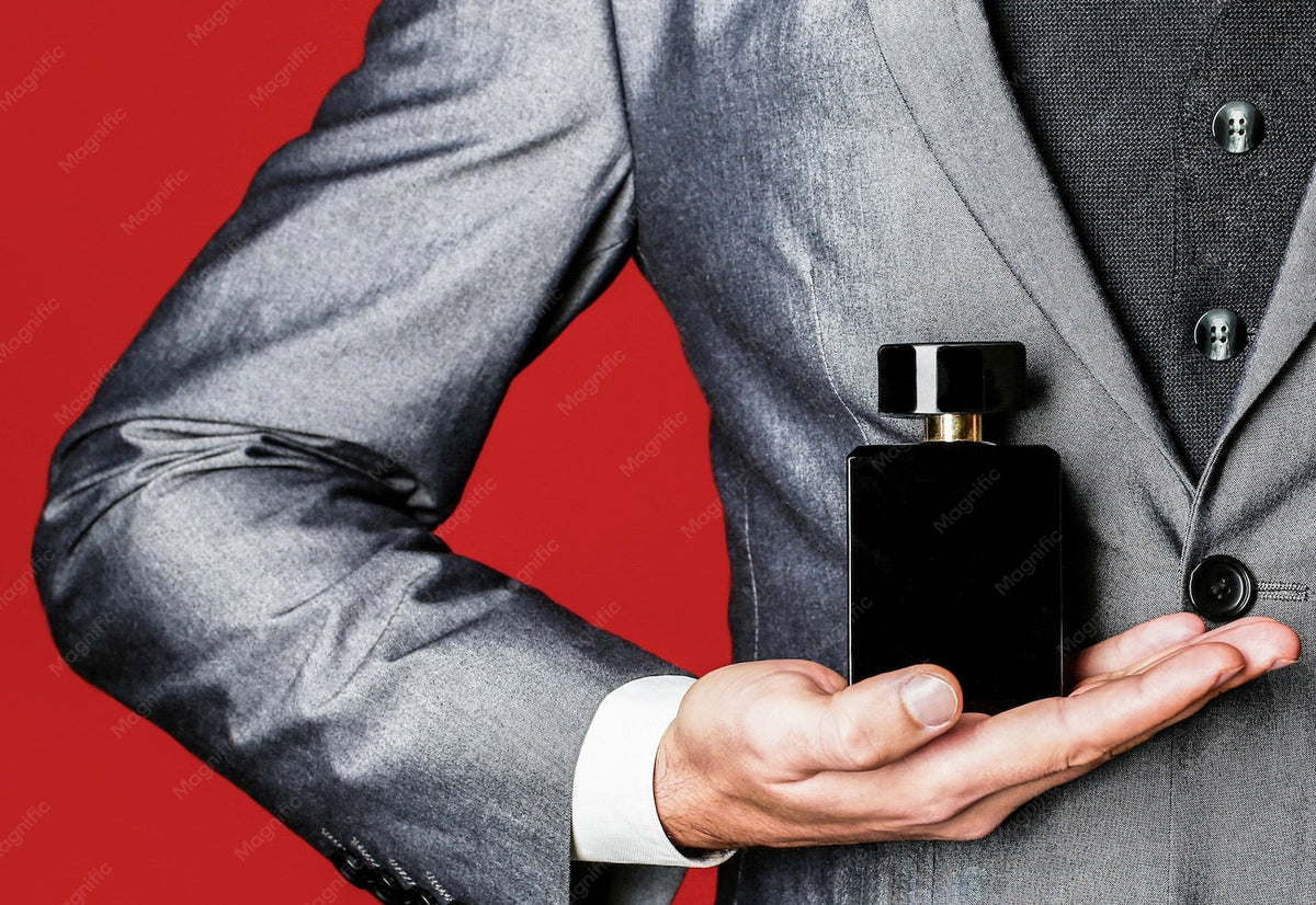  Man holding up a unisex perfume bottle in the hand on suit background